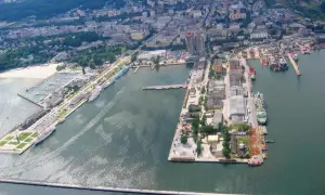 Rozległy port morski z licznymi statkami, jachtami i budynkami przemysłowymi.