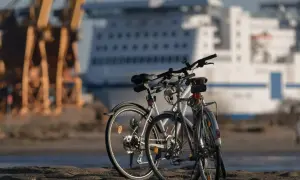 Dwa rowery czekają na swój rajd rowerowy przy nabrzeżu. W tle ogromny statek wycieczkowy i dźwigi portowe.
