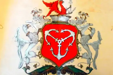 Herb Gdyni: czerwona tarcza z białym kotwicą, podtrzymywana przez dwa gryfy. Na górze czerwony smok i kotwica.