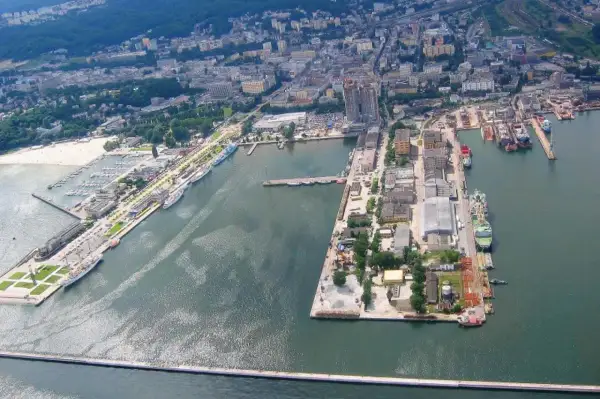 Rozległy port morski z licznymi statkami, jachtami i budynkami przemysłowymi.