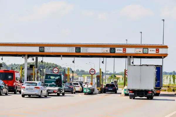 Kork na autostradzie bursztynowej. Samochody i ciężarówki czekają na bramkach opłat.