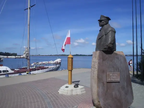 Pomnik upamiętniający zaślubiny Polski z morzem. Obok żaglowiec i polska flaga.