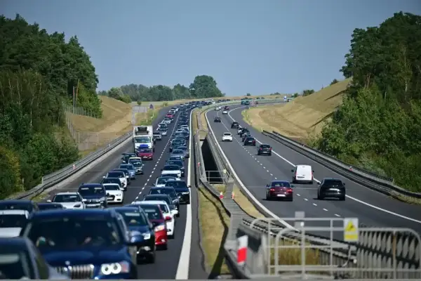 Długi korek samochodów na autostradzie A6. Wiele pojazdów stoi w powolnym ruchu, otoczonych zielenią drzew.